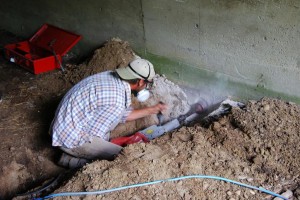 Jeff drilling a hole in the shed foundation for the wash station drain.